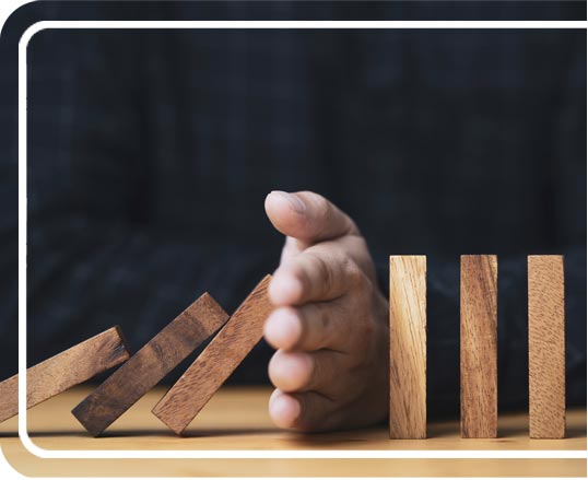 A hand stopping a set of domino blocks from continuing