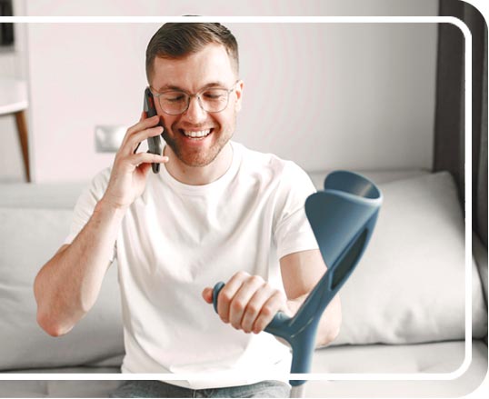 A smiling man with crutches on the phone