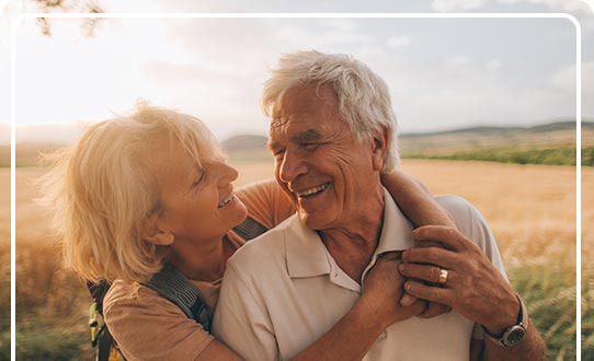 A retired couple walking in nature at sunset