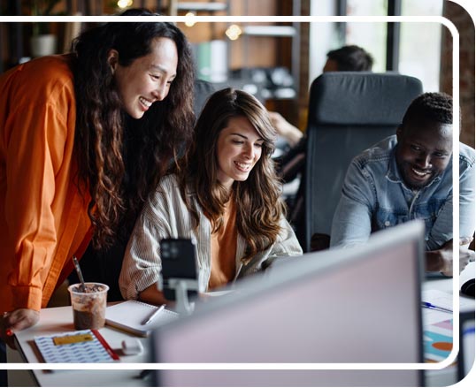 coworkers clustered around a computer screen smiling and talking