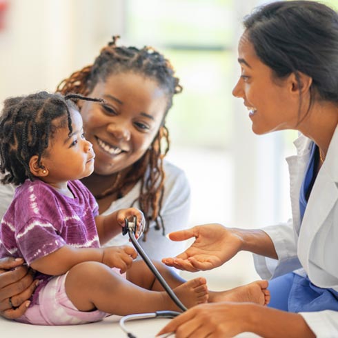 A smiling female doctor talking to a child and her mother