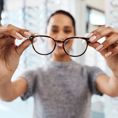 Woman Holding up her new Glasses and smiling