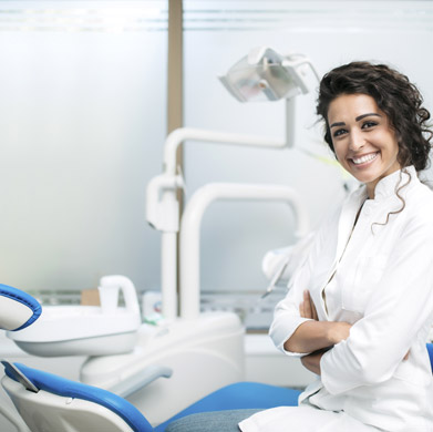 a smiling female dentist in front of her dentist chair and equipment